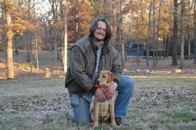 Smiling long haired man with dog in park portrait