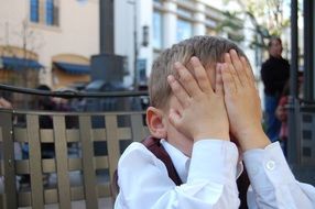 the child covers his face with hands from fatigue