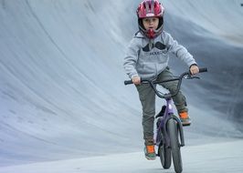 child in a helmet rides a bicycle