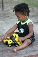 dark-skinned kid plays with a toy car