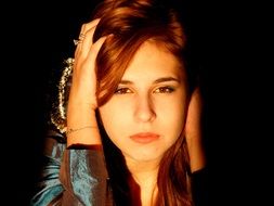 Girl with brown hair holds hands on head