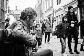 Black and white image of a street musician among people