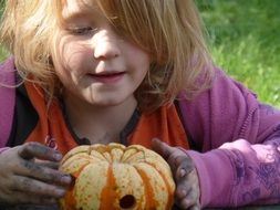 little girl playing with a little pumpkin