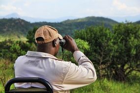 man looking through binoculars in africa