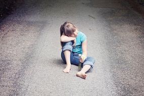 Child is sitting on a road