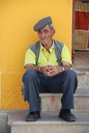 elderly Portuguese is sitting on the stairs