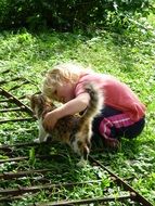 little girl plays with cat on the street