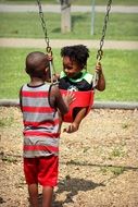 boy rolls a child on a swing