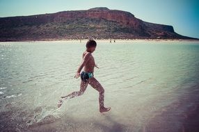 child runs on water at the beach