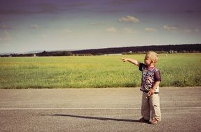 boy with hand raised on the road