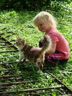 girl is playing with a kitten in the garden