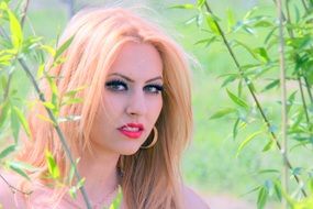 nice girl with blond hair on the background of green nature
