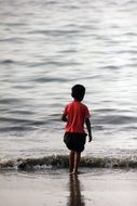 Indian kid is walking on a sandy beach