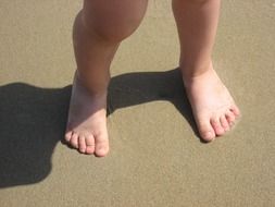 bare feet of the kid in the sand