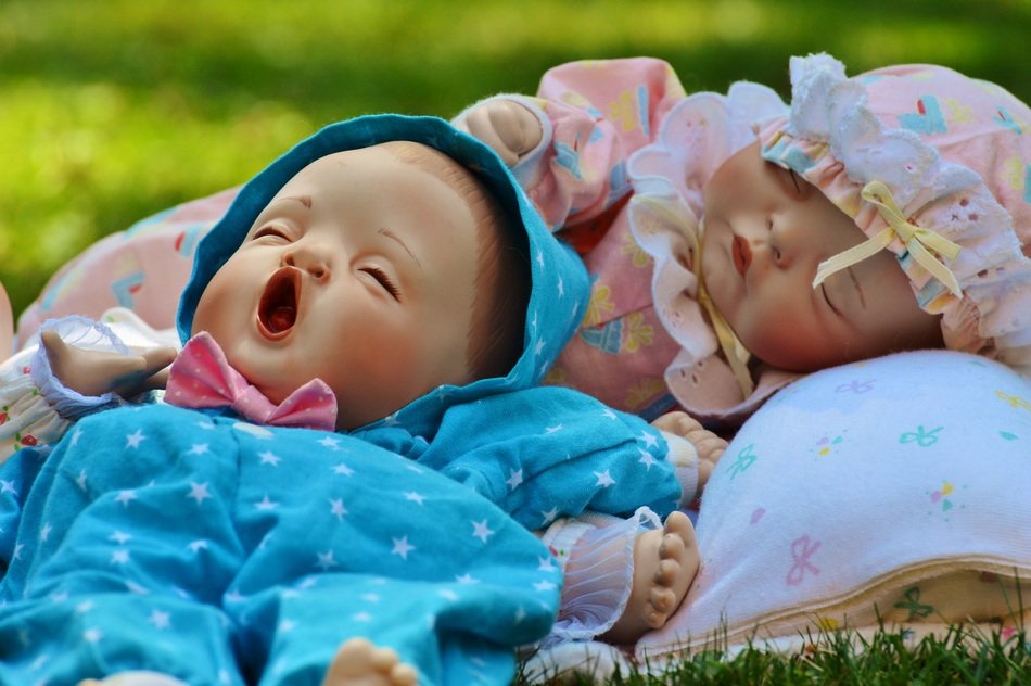 sleeping dolls on green grass on blurred background