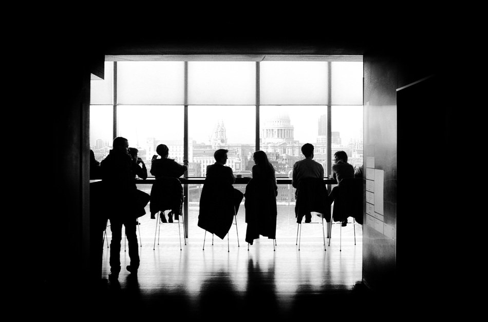 silhouettes of people on chairs near the window