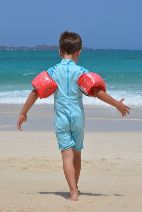 A boy on the beach with rubber rings in his hands