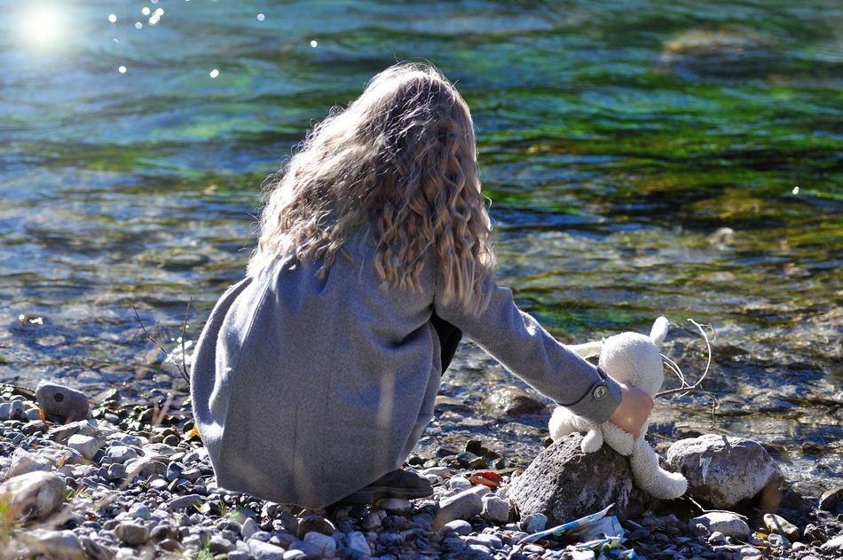 girl and teddy bear by the lake