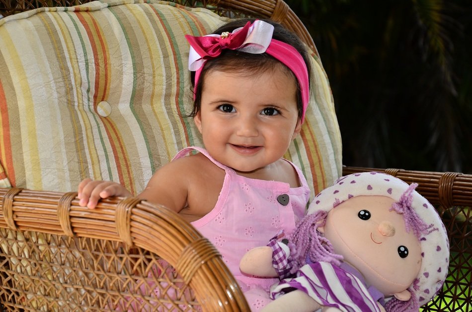 little girl with a doll on the armchair