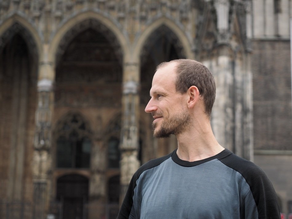 photo of a smiling man against the background of an antique cathedral