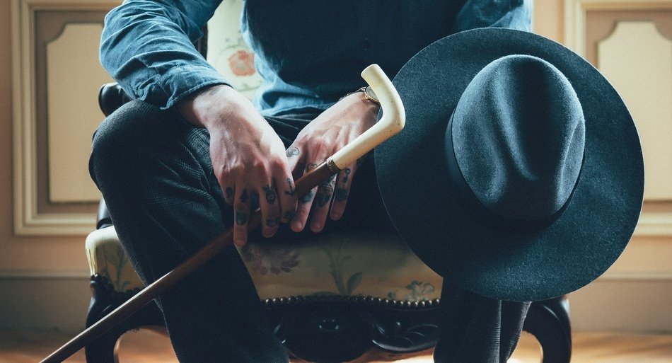 man sits with a cane and hat