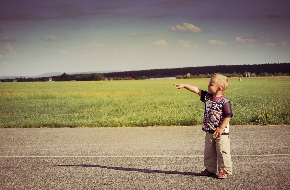 boy with hand raised on the road