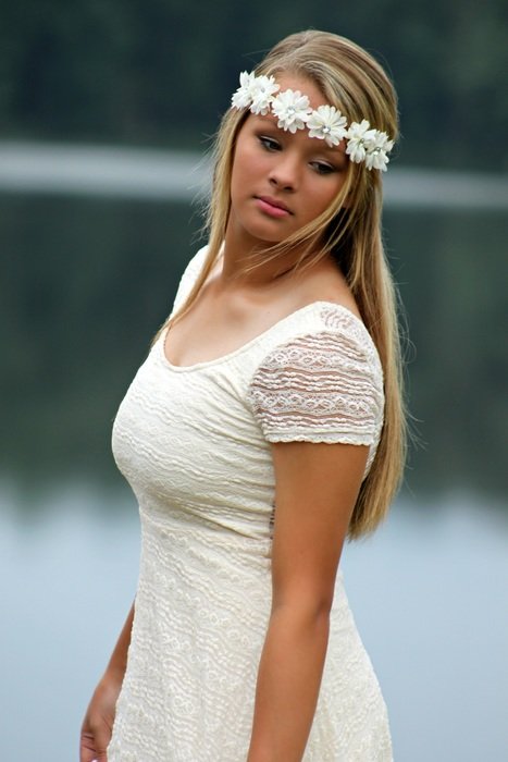 Girl in white dress and wreath on the river bank