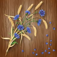 Cornflowers and wheat ears on wood background