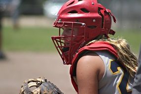 girl in a red helmet plays softball