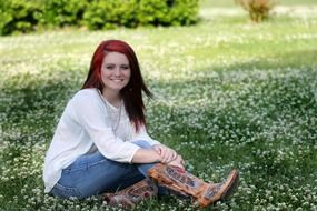 girl sitting on green grass with daisies