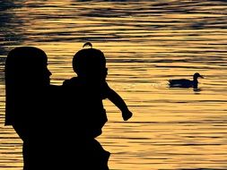 silhouette of mater and child by the lake