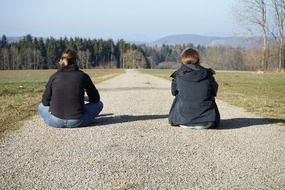 girlfriends sitting on path road forest view