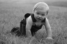 Black and white photo of baby crawling on a grass