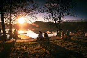 people on a picnic on the lake at sunset