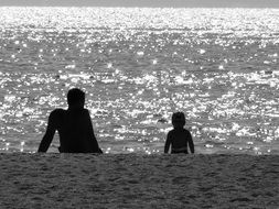 Black and white photo of baby and father on a beach