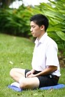 buddhist, asian boy meditating on lawn