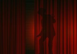 silhouette of a man behind a red curtain