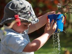 boy is playing with a holey bucket in the garden