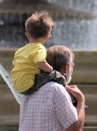 baby sits on daddy's shoulders