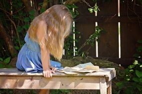 blond girl sitting in the garden with letters