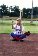 female softball player sitting on base on field