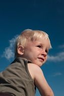 blond baby on blue sky background