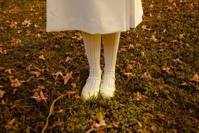 legs of a girl in white pantyhose and white sandals