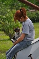 young girl holding small dog outdoor