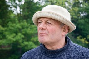man stands thoughtfully near green trees