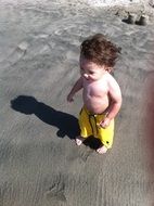 baby in yellow shorts on the beach