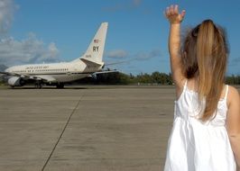 girl in a white dress waving goodbye to the plane