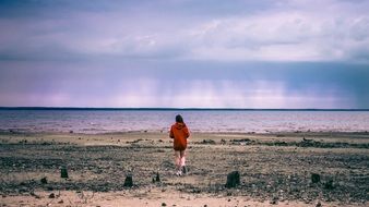 girl in a red sweater on a cloudy beach