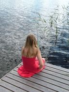 sitting girl in a dress on a wooden pier