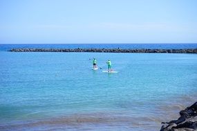 stand up paddling men in sea